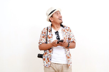Happy Asian adult man tourist holding a cell phone while looking something on empty space. Concept of travel. Isolated on white background