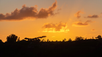 Fototapeta na wymiar Panorama of orange sunset view of ridge in silhouette near Kilauea, Kauai, Hawaii, United States. 