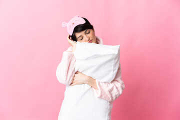 Woman with short hair isolated on pink background in pajamas and holding a pillow while sleeping