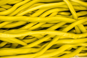 Pile of yellow ethernet network cables that look like yellow string sweets candy.
