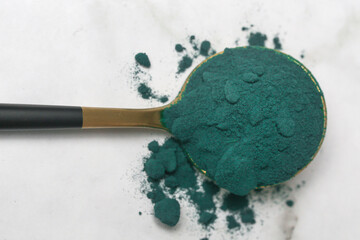 Green powder in the spoon, spirulina, alage, chlorophyll or matcha. Concept of nutritional...