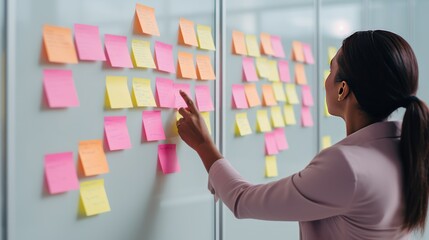 Woman organizer attaches colorful sticky notes to white board. Life hack for easy memorization and reminders of important things in visible place in office. Organization of space and clear schedule.