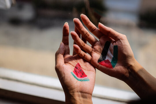 Hands painted with Palestine flag and watermelon slice, as symbol of support for Palestine.