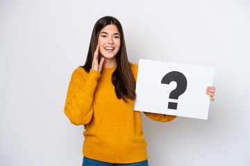 Young Brazilian woman isolated on white background holding a placard with question mark symbol and...