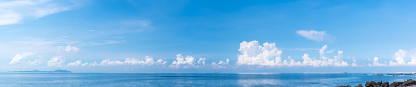 Panoramic blue sky with white fluffy clouds and sea