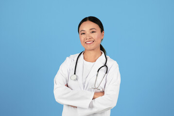 Fototapeta premium Portrait Of Smiling Asian Doctor Woman In Uniform Standing With Arms Crossed