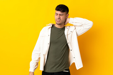 Young Colombian man isolated on yellow background with neckache