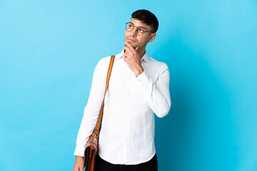 Young business Colombian man isolated on blue background having doubts