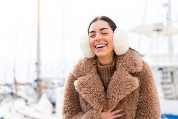 Young woman wearing winter muffs at outdoors smiling a lot - obrazy, fototapety, plakaty