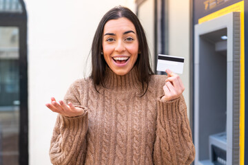 Young woman holding a credit card at outdoors with shocked facial expression