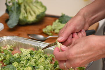 woman cutting broccoli into chicken fillet for baking 12