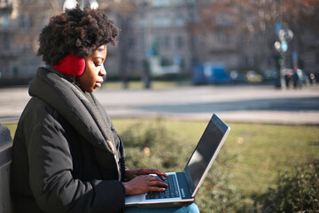 young woman sitting on a bench uses a computer