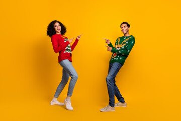 Fototapeta na wymiar Full length photo of funny funky guy girl dressed christmas ugly print pullovers showing fingers empty space isolated yellow color background