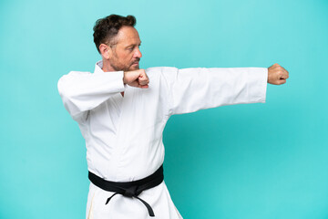 Middle age caucasian man isolated on blue background doing karate