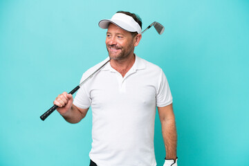 Middle age caucasian golfer player man isolated on blue background looking to the side and smiling