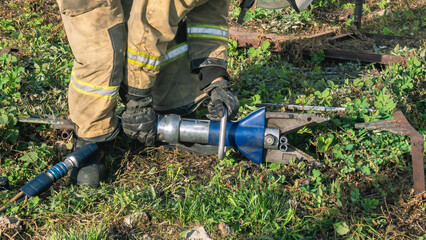 A lifeguard in protective clothing uses hydraulic scissors to cut through the metal structure. A...