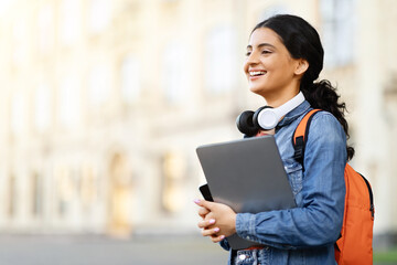 Excited pretty young indian woman student with backpack and laptop