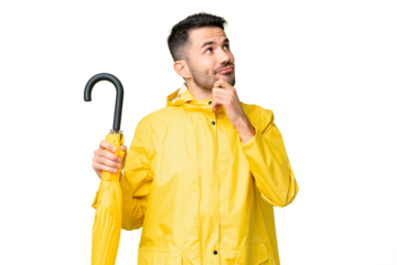 Young caucasian man with rainproof coat and umbrella over isolated background having doubts