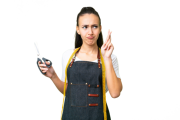 Young Seamstress woman over isolated chroma key background with fingers crossing and wishing the best