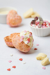 Pink heart shaped cookies drizzled with white icing and sprinkled with little hearts. Preparation for Valentine's Day..