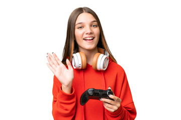 Teenager caucasian girl playing with a video game controller over isolated background saluting with hand with happy expression