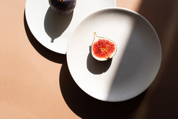 Still life with figs and plates. Photos in natural colors. Minimal food concept with dramatic light and shadow