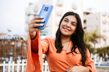 A young latin american woman taking a selfie with a mobile phone.