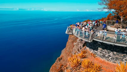 Gordijnen Tourists enjoy the viewpoint at Cabo Girao, along the Madeira coastline, Portugal. Aerial view from drone © jovannig