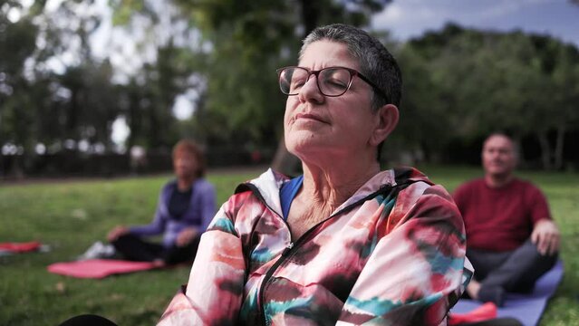 Senior sports people relaxing in yoga meditation practice at City Nature. Health care, older community concept