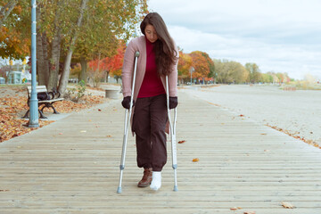 woman with a broken foot walking on a wooden bridge