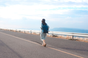 Rear view of young woman traveler with backpack freedom travel minimal background with blue sky - obrazy, fototapety, plakaty