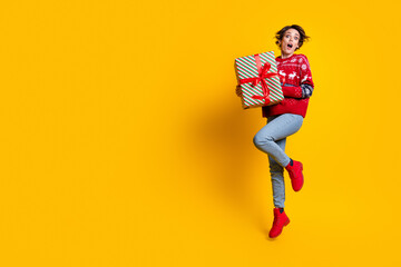 Full body photo of impressed astonished woman wear sweater hold present box jumping near empty...
