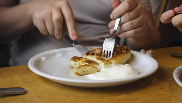 Dinner at the restaurant. A man eats potato pie with sour cream. Close-up.