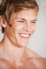 Obraz premium Man, topless and smile in studio or white background for positive energy, healthy or confidence. Male person, model or shirtless relax masculine for strong shoulders or attractive, calm or muscle