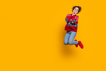 Fototapeta na wymiar Full body photo of girlish woman wear sweater jumping hold arms on cheekbones near logo empty space isolated on yellow color background