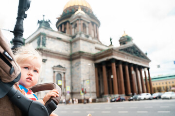 Cute baby child in a stroller on the background of St. Isaac's Cathedral in St. Petersburg