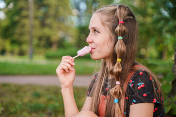 Young teen girl eating popsicle ice cream in summer park
