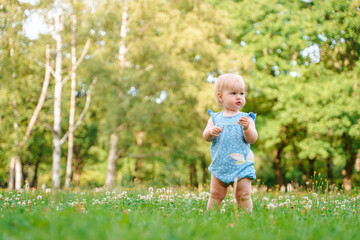 Cute baby child girl enjoys summer in a green park