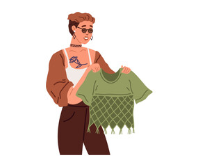 Woman chooses trendy t-shirt for party in womens clothing store. Person stands holds blouse in hands in dress market. Fashion designer, dressmaker, sewing specialist during work. Lady looks at outfit