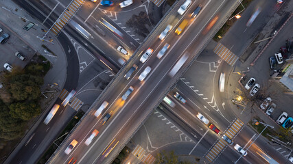 A busy intersection with a lot of cars, buses and trucks. Aerial view from the drone on the night road, the city and pedestrians. Lights and headlights are shining. A traffic jam has formed. Almaty - obrazy, fototapety, plakaty