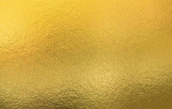 Gold wall texture background. Yellow shiny gold foil paint on wall sheet with gloss light reflection, vibrant golden paper luxury wallpaper