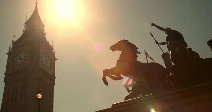 Big Ben, Houses of Parliament, Union Jack flag and Boadicea or Boudica statue on Westminster Bridge at sunset, London, England