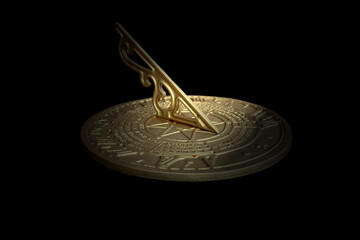Antique brass sundial with time and calendar engraved on the surface. Isolated on black background - obrazy, fototapety, plakaty
