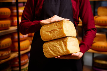 Man holding cheese brocks in specials place for cheese storage and production. Eco food. Aged cheese. Concept of food, taste, art of organic products, healthy, natural food.