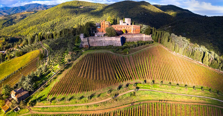 Italy, scenery of Tuscany. aerial drone view of beautiful medieval castle Castello di Brolio in Chianti region surrounded by golden autumn vineyards - obrazy, fototapety, plakaty
