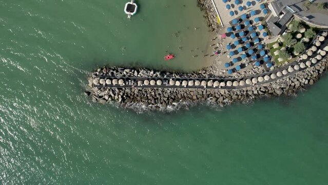 Aerial view of people sunbathing under umbrellas at San Terenzo Beach, Lerici, Italy.