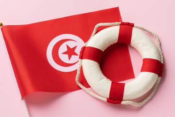 Tunisian flag and lifebuoy on a colored background, concept on the theme of helping Tunisia