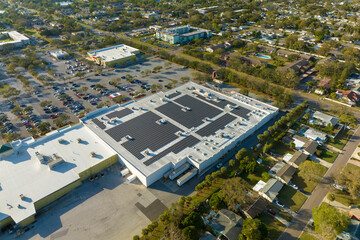 Solar power plant with blue photovoltaic panels mounted on commercial shopping store building roof for producing green ecological electricity. Production of sustainable energy concept