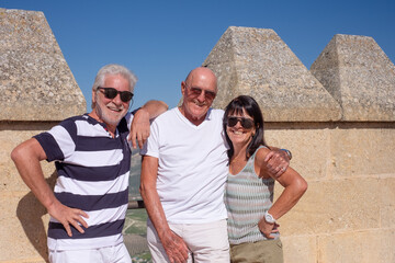 Caucasian group of happy senior people visiting a historic castle in Andalusia, Spain, posing at the top for a souvenir photo. Travel and tourism concept, adventure is ageless