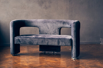 An elegant dark-colored sofa on a dark wall. One object on a dark background with space to copy....